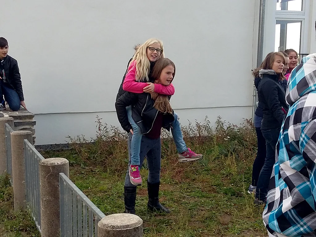 Zwei Jugendliche tragen sich huckepack.